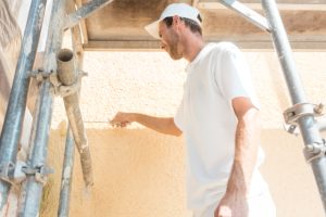 Painter Working on a Wall on the exterior of a home