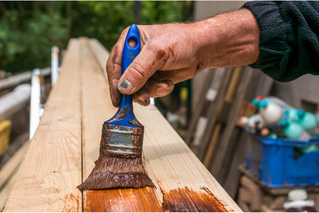 Painter with paintbrush painting wood