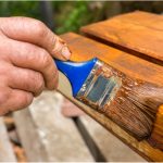 Painter with paintbrush painting wooden surface